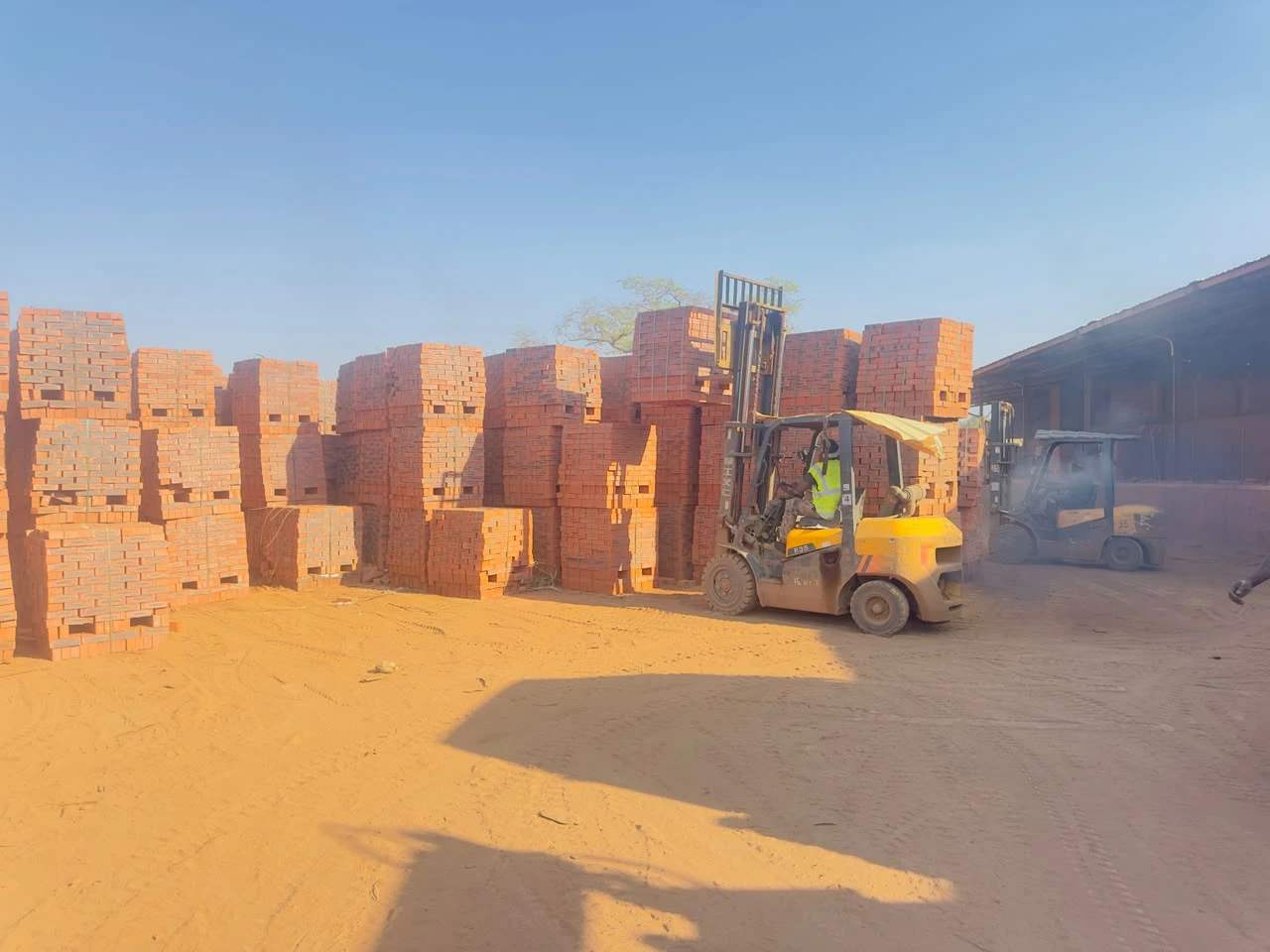 A forklift working between rows of stacked brick pallets on the AfroPacific site in Ruwa